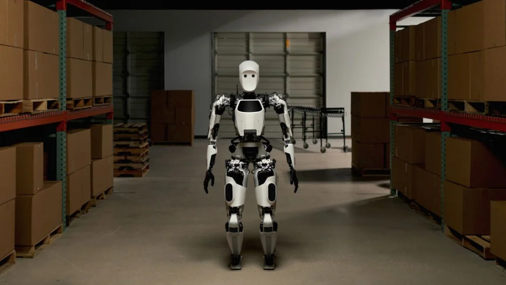 Apptronik Apollo standing between warehouse shelves