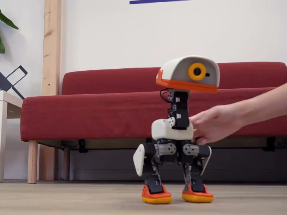 Microduck standing beside a sofa during a balance demonstration